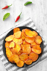 Plate with yummy sweet potato chips on table
