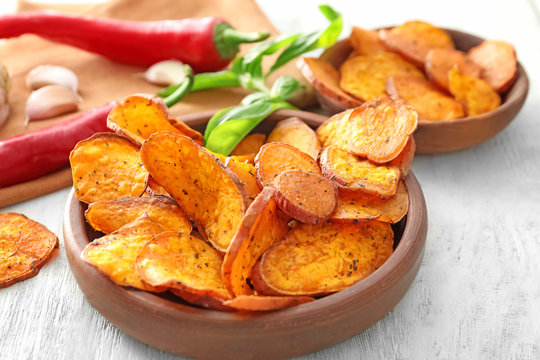 Bowl with yummy sweet potato chips on table