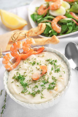 Tasty cream soup with fresh shrimps in bowl on table