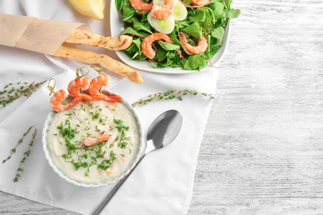 Tasty cream soup with fresh shrimps in bowl on table