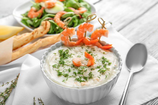Tasty cream soup with fresh shrimps in bowl on table