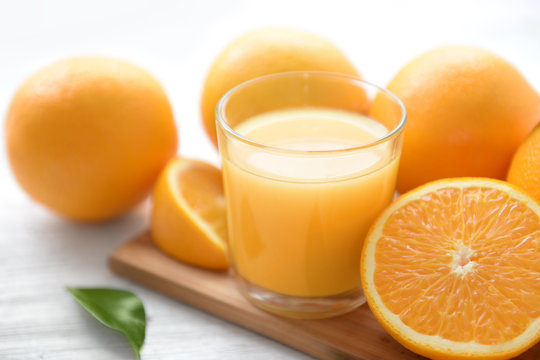 Glass of orange juice with fruit on wooden board