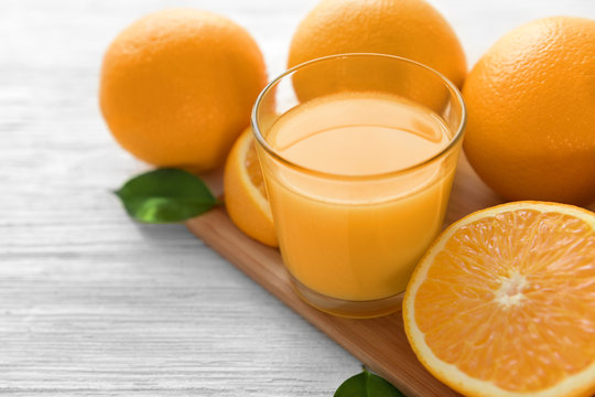 Glass of orange juice with fruit on wooden table