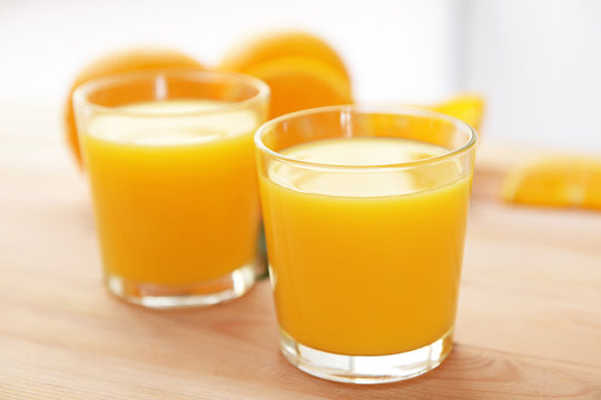 Glasses with yummy fresh orange juice on wooden table