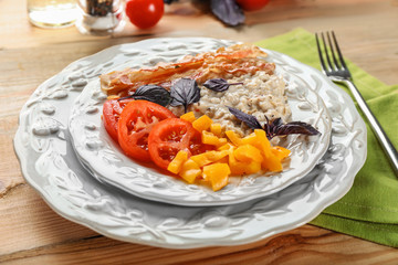 Plate with oatmeal porridge, bacon and garnish on table