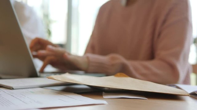 Young Accountant Woman Puts On Glasses and Start Working on Computer Laptop. Glasses Laying on Table in Office. 4K, closeup.