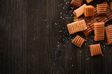 Tasty caramel candies on wooden table