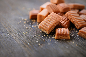 Tasty caramel candies on wooden table