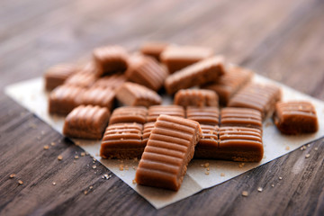 Tasty caramel candies on wooden table