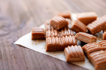 Tasty caramel candies on wooden table