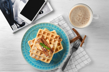 Plate with delicious cinnamon waffles on table
