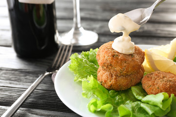 Pouring sauce onto salmon patties in plate