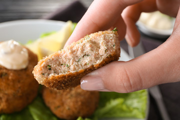 Woman holding tasty salmon patty, closeup