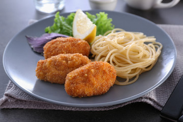 Plate with tasty salmon croquettes and spaghetti on table