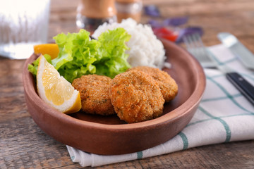Plate with tasty salmon patties on table