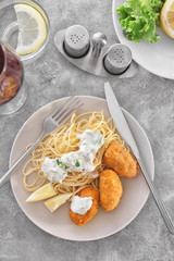 Plate with tasty salmon croquettes and spaghetti on table