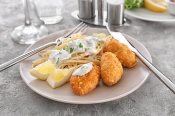 Plate with tasty salmon croquettes and spaghetti on table