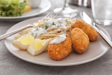 Plate with tasty salmon croquettes and spaghetti on table