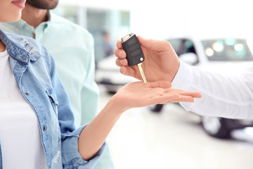 Obraz na płótnie Canvas Car salesman giving key to couple in dealership