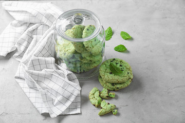 Jar with mint chocolate chip cookies on table