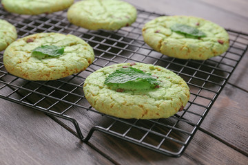 Baking grid with mint chocolate chip cookies on wooden table, closeup