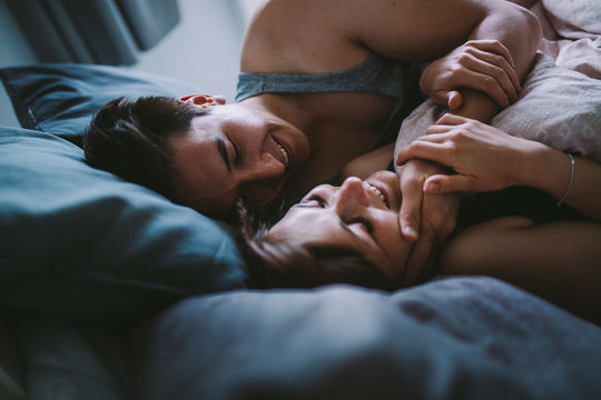 Happy couple cuddling in cozy bed in morning