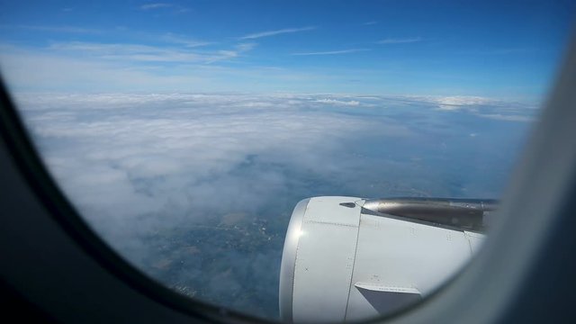 plane window and jet engine flying over white cloud