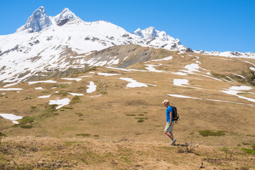 Traveler, with backpack, walks along mountain plateau