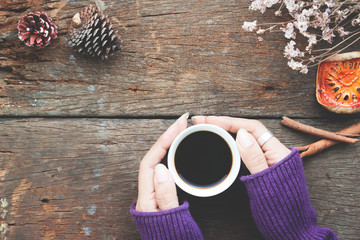 Woman hands holding cup of hot coffee on wooden table, Overhead view fall and winter concept
