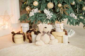 Xmas Christmas gifts and bear under the Christmas tree. Christmas tree with balls, garlands, in gold colors. The concept of Christmas and happy new year.