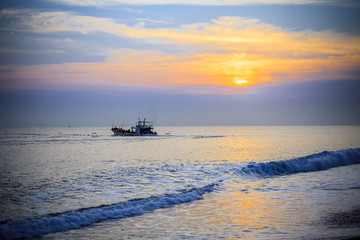 Landscape South China Sea. Asian theme with rocky beach and Chinese fishing junks in background under blue skies with puffy clouds. 