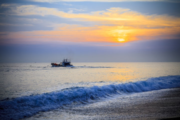 Fototapeta premium Landscape South China Sea. Asian theme with rocky beach and Chinese fishing junks in background under blue skies with puffy clouds. 