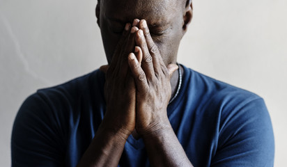 Black man with hands covered his face feeling worried