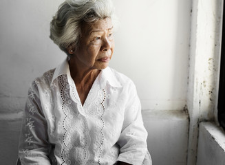 Elderly asian woman looking out of the window