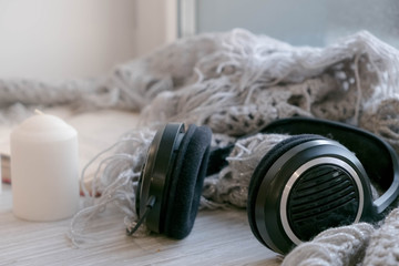Soft photo Christmas music. Headphones Hot coffee in mug with plaid or scarf, winter window vintage table surface, selective focus. Cozy winter home morning holiday. Lifestyle Concept. Hygge style
