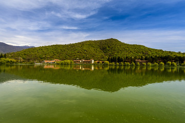 Rural lake landscape with wildlife, ducks and snow capped mountains in background with blue skies and clouds midst of fall foliage.  
