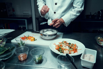 Chef prepares the sauce. Holds a spoon in his hand. Cooking. Professional kitchen. Salad dressing
