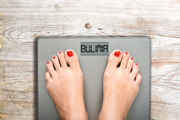 Health and care concept with bulimia word on bathroom scale while a woman is weighting - obrazy, fototapety, plakaty