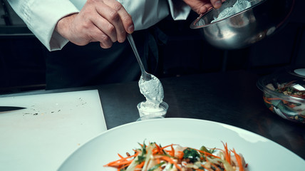 Chef prepares the sauce. Holds a spoon in his hand. Cooking. Professional kitchen. Salad dressing