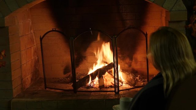 Fire in a fireplace, 4k, slow motion. woman drink tea near the fireplace