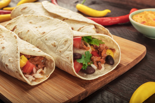 Closeup of Mexican burritos with beef, rice, and chili peppers