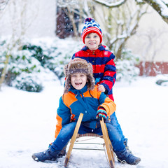 Two little kid boys enjoying sleigh ride in winter