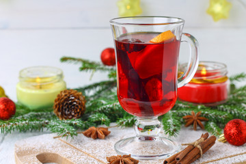 New Year's mulled wine in a glass on the background of twigs, candles and garlands.