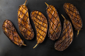grilled glazed eggplants on black background