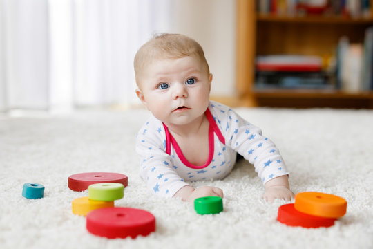 Cute baby girl playing with colorful wooden rattle toy