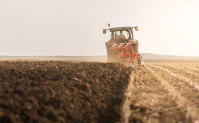 Fototapeta premium Tractor plowing fields -preparing land for sowing in autumn