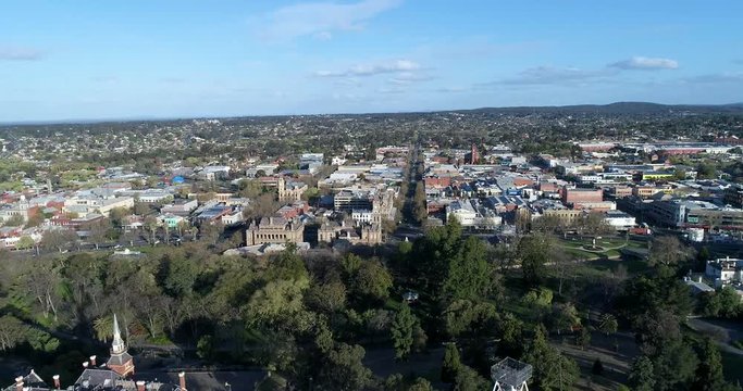 Central town hill park with lookout tower to Town Hall and downtown streets aerial forward panning.
