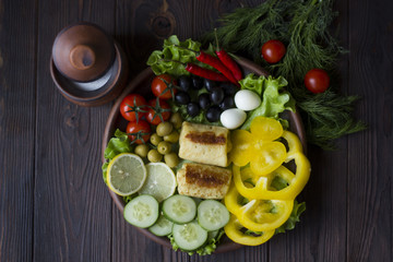 pancakes and fresh organic vegetables: tomatoes, peppers, parsley, lemon, cucumber, chili, spices and olives in a clay plate on the table dark wood