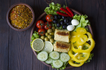 pancakes and fresh organic vegetables: tomatoes, peppers, parsley, lemon, cucumber, chili, spices and olives in a clay plate on the table dark wood