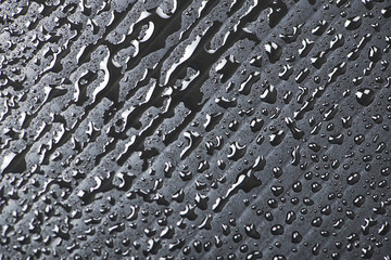 Abstract background of water droplets on black surface.